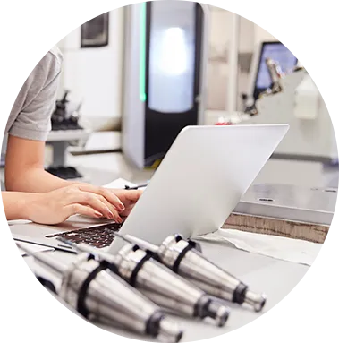 Engineer working at a laptop beside CNC tool holders